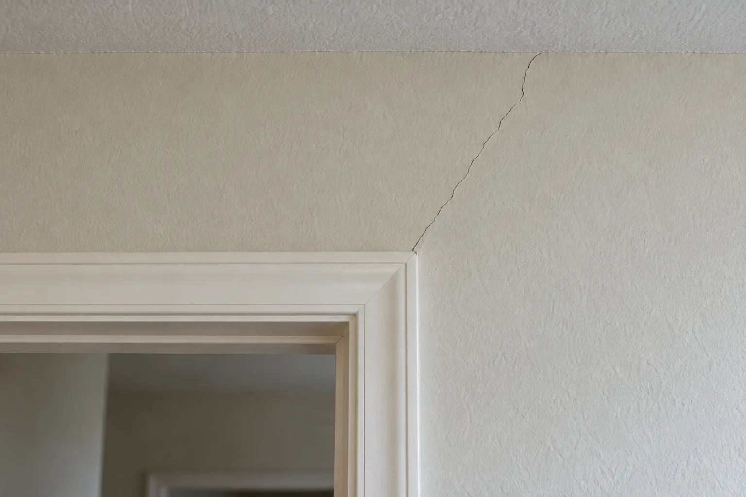 Fine diagonal crack running from the top corner of a doorway up to the ceiling